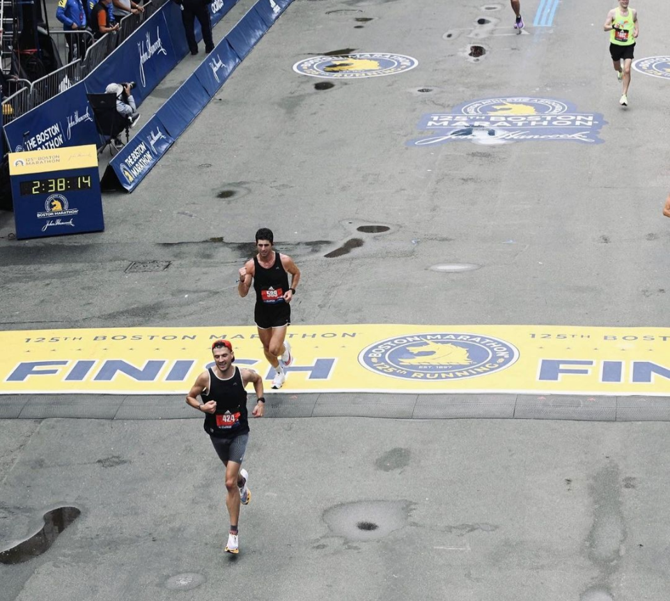 Two runners crossing the finish line at the Boston Marathon, with a time of 2:38:14.