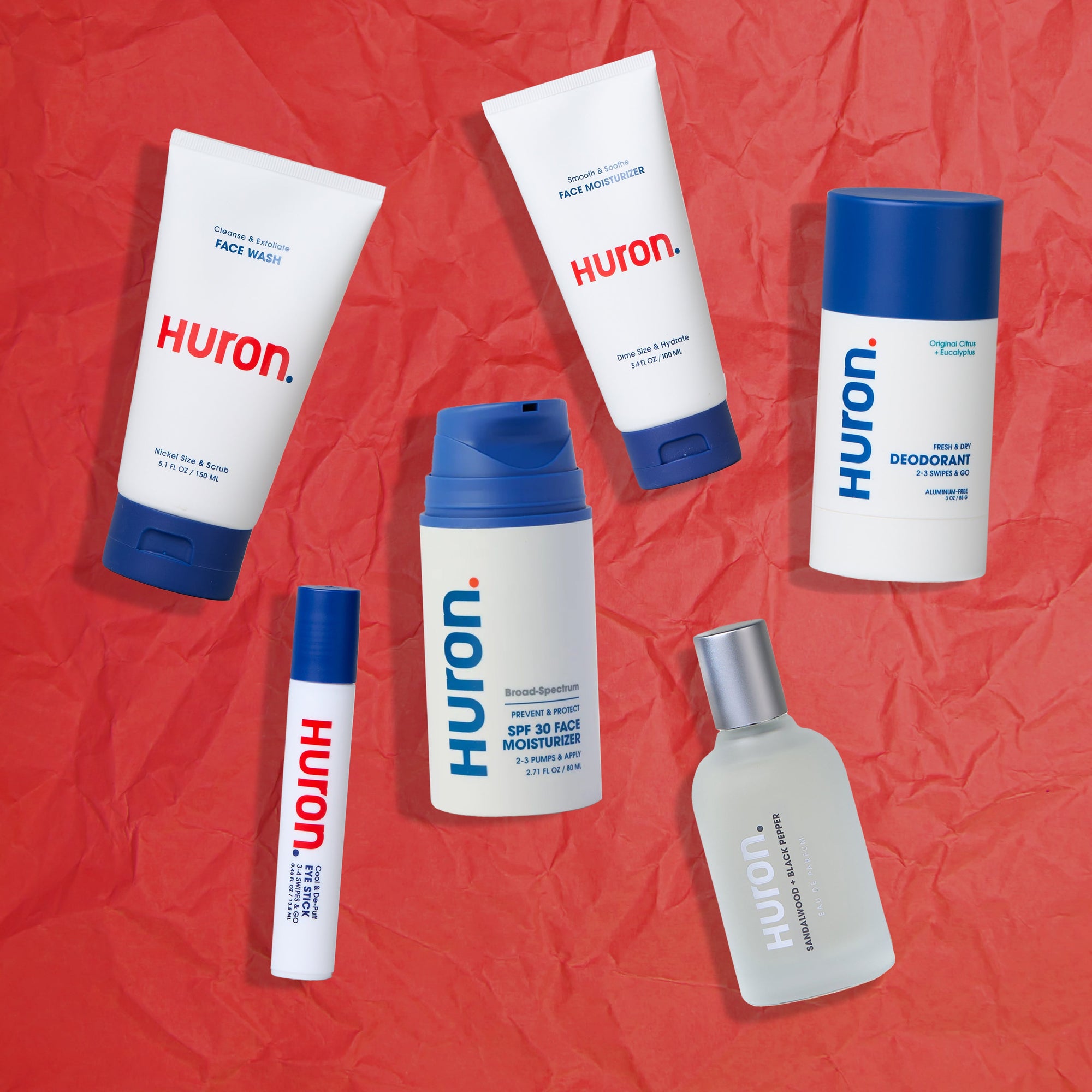 Various Huron skincare products including face wash, moisturizer, deodorant, and more on a red background.