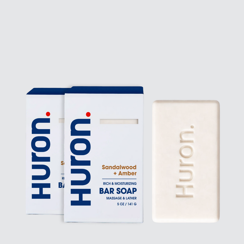 Front view of Huron Sandalwood and Amber bar soap pack showing embossed Huron logo and white retail boxes on light gray background #scent_sandalwood + amber