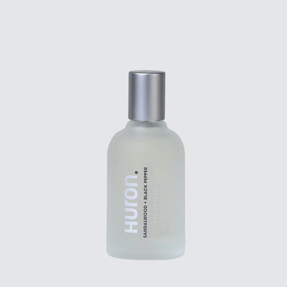 Frosted glass cologne bottle labeled HURON — text: SANDALWOOD + BLACK PEPPER #scent_sandalwood + black pepper