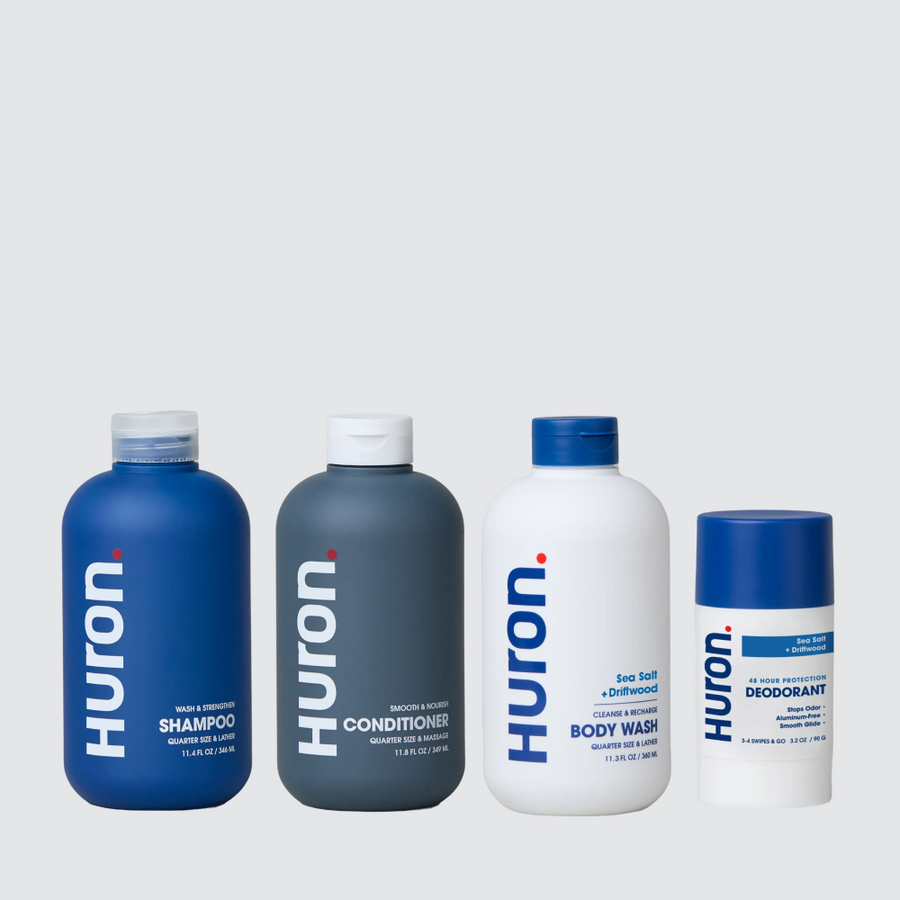 Front view of Fave Four Bundle showing Huron shampoo, conditioner, body wash, and deodorant in Sea Salt and Driftwood scent on a light gray background