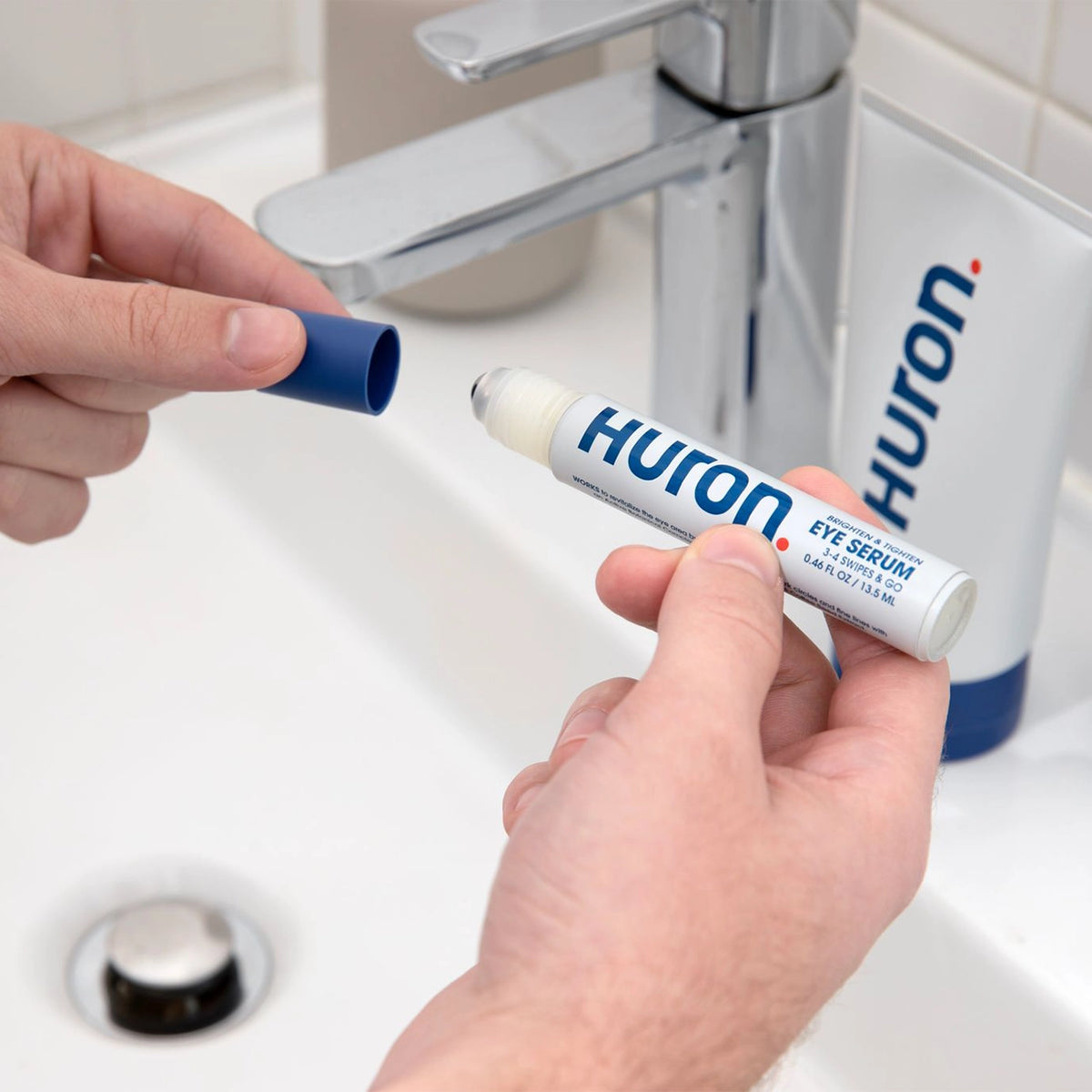 Person holding Huron Eye Serum applicator in front of a sink