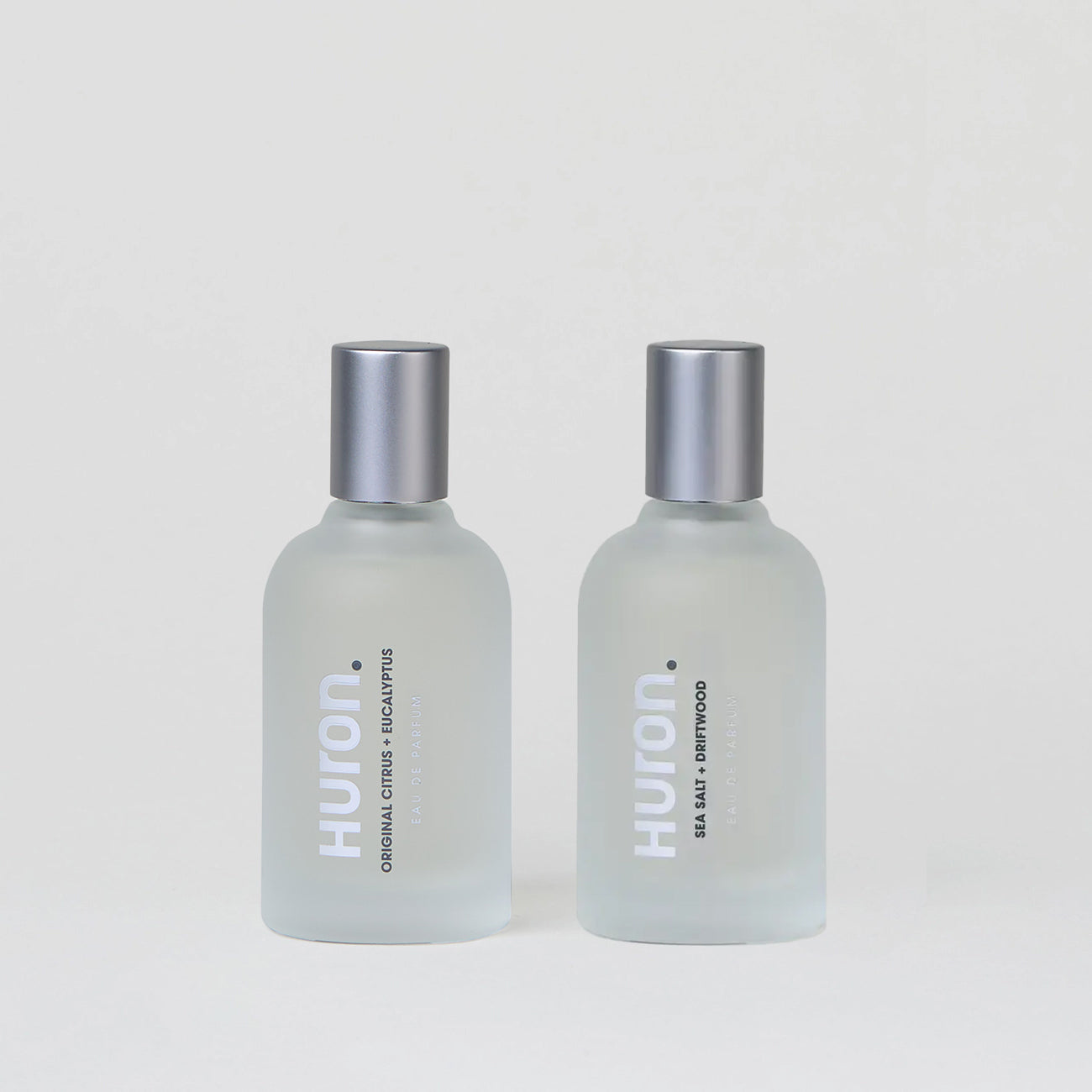 Two frosted glass bottles labeled 'Huron' containing cologne, with silver caps.