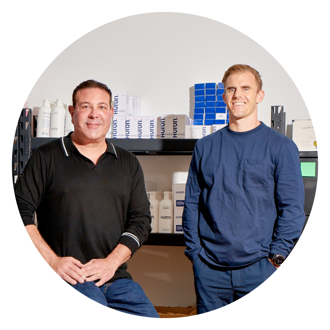 Two men standing in front of personal care products, promoting personal care.