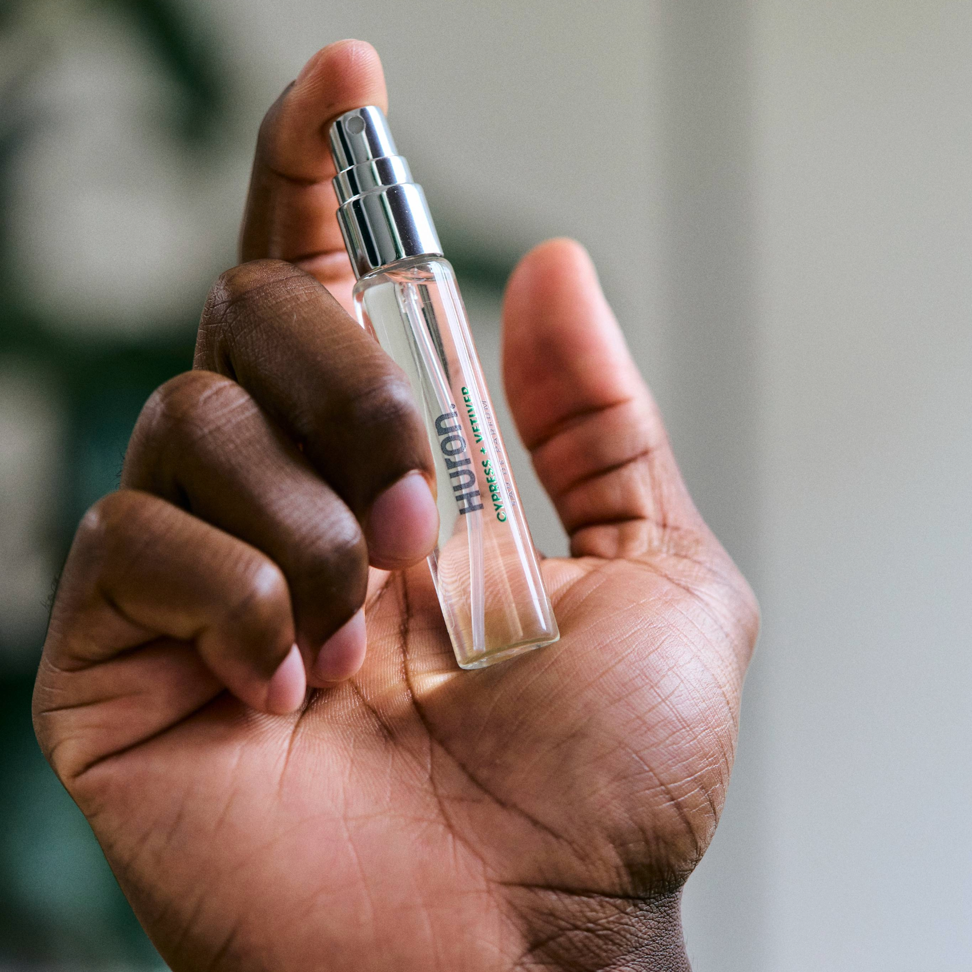 Hand holding a small spray bottle labeled 'Huron Cypress + Vetiver'
