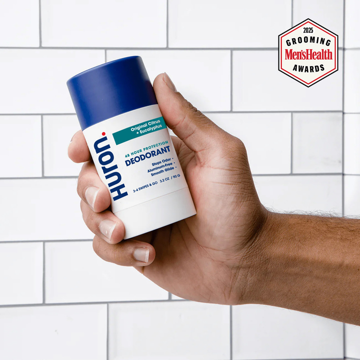 Huron deodorant stick labeled 'Original Citrus + Eucalyptus' held in a hand; Men's Health 2025 grooming award badge. #scent_Original Citrus + Eucalyptus