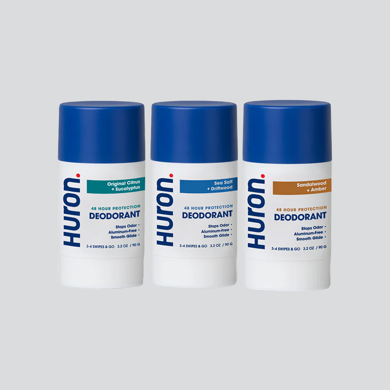 Three Huron deodorant sticks labeled Original Citrus + Eucalyptus, Sea Salt + Driftwood, and Sandalwood + Amber, each with 48 hour protection and aluminum-free formula.
