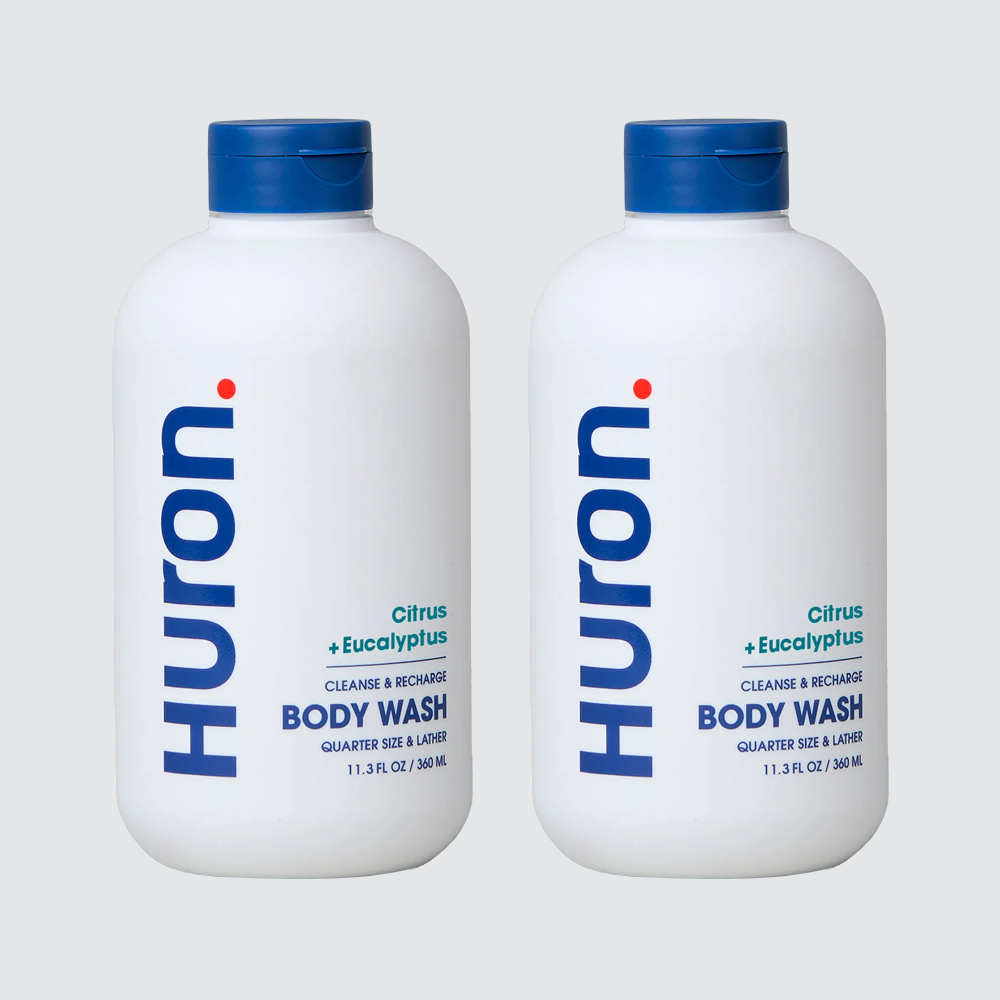 Front view of two Huron Citrus + Eucalyptus body wash bottles (11.3 fl oz) with blue caps on light gray background