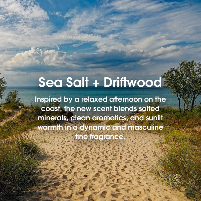 A beach scene with text: 'Sea Salt + Driftwood Inspired by a relaxed afternoon on the coast, the new scent blends salted minerals, clean aromatics, and sunlit warmth in a dynamic and masculine fine fragrance.'