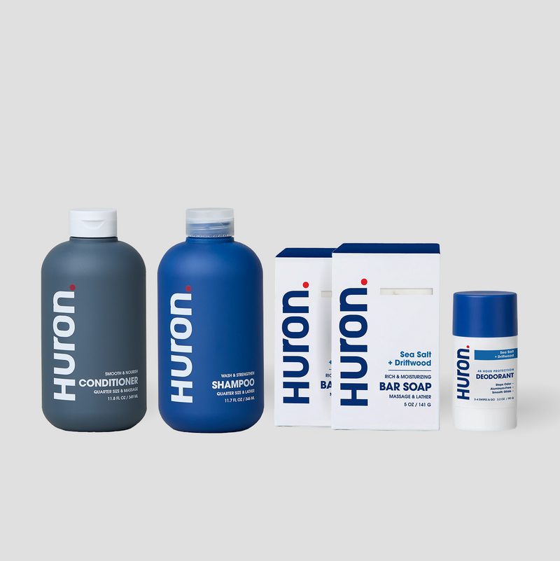 Huron shampoo and conditioner bottles, two Sea Salt + Driftwood bar soap boxes, and Huron deodorant on gray background #scent_sea salt + driftwood
