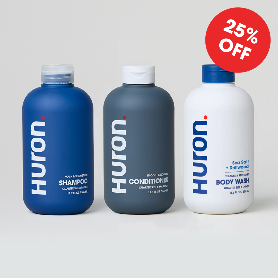 Three Huron personal care products: shampoo, conditioner, and body wash in blue and white bottles.#scent_sea salt + driftwood