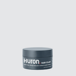 Front view of Huron Hair Clay tub showcasing the brand label and 2.77 fl oz size on a light gray background
