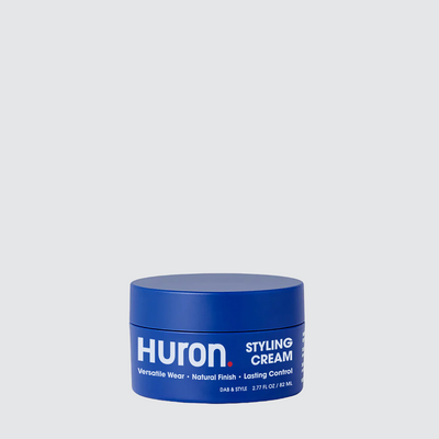 Blue round jar labeled HURON STYLING CREAM on pale background