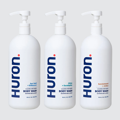 Front view of three Huron jumbo body wash bottles (Sea Salt, Citrus, Sandalwood), 30.2 fl oz each on light gray background