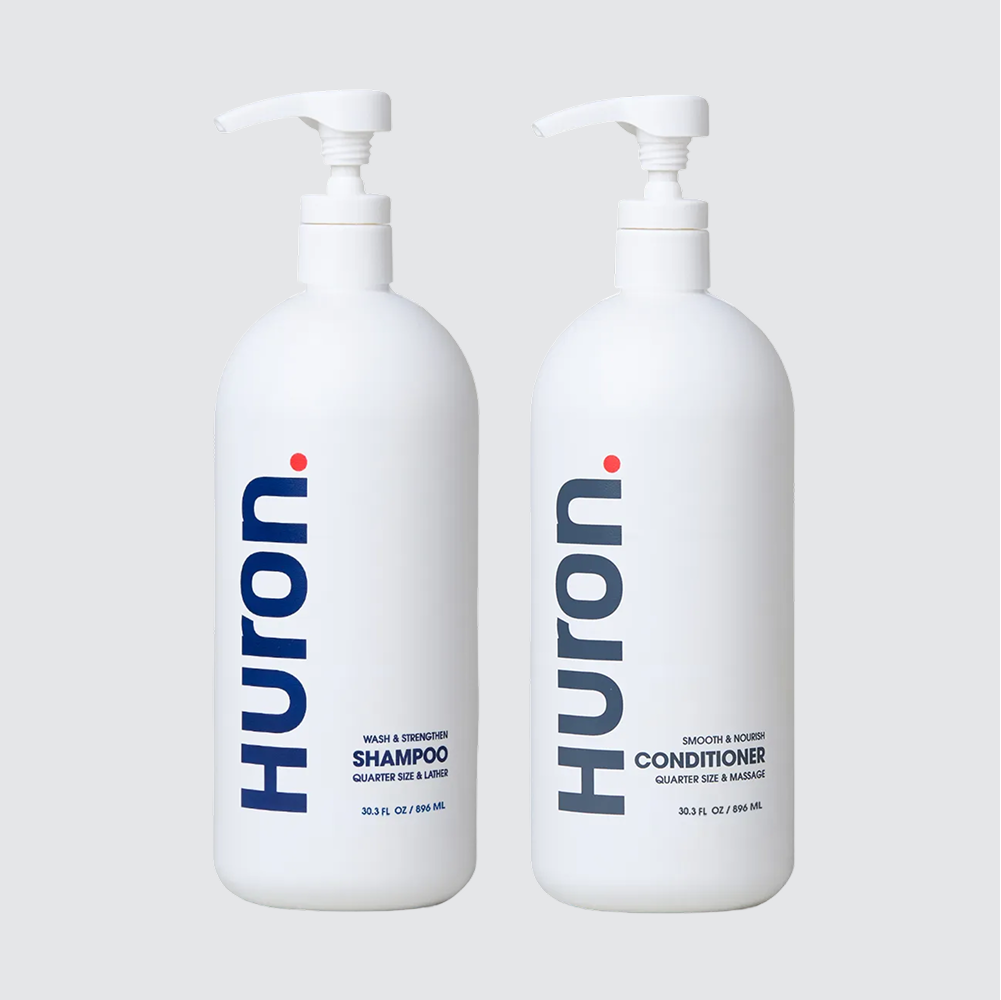 Front view of two jumbo Huron pump bottles: Shampoo and Conditioner showing vertical Huron logo and 30.3 fl oz size on light gray background