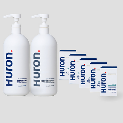 Two white Huron pump bottles labeled Shampoo, Conditioner, and 5 white cartons labeled Huron Bar Soap — Citrus + Eucalyptus scent. #scent_citrus + eucalyptus