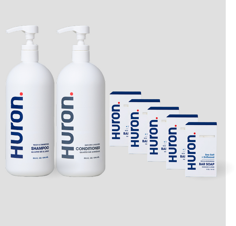 Two white Huron pump bottles labeled Shampoo, Conditioner, and 5 white cartons labeled Huron Bar Soap — Sea Salt + Driftwood scent. #scent_sea salt + driftwood