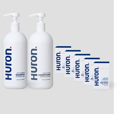 Two white Huron pump bottles labeled Shampoo, Conditioner, and 5 white cartons labeled Huron Bar Soap — Sea Salt + Driftwood scent. #scent_sea salt + driftwood