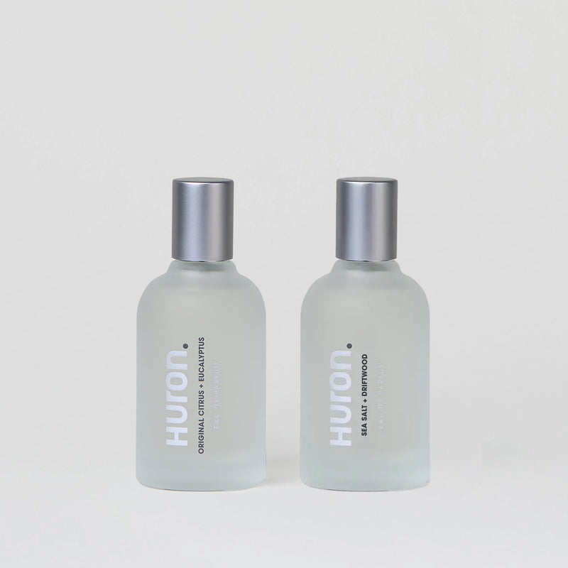 Two frosted glass bottles labeled 'Huron' containing cologne, with silver caps.