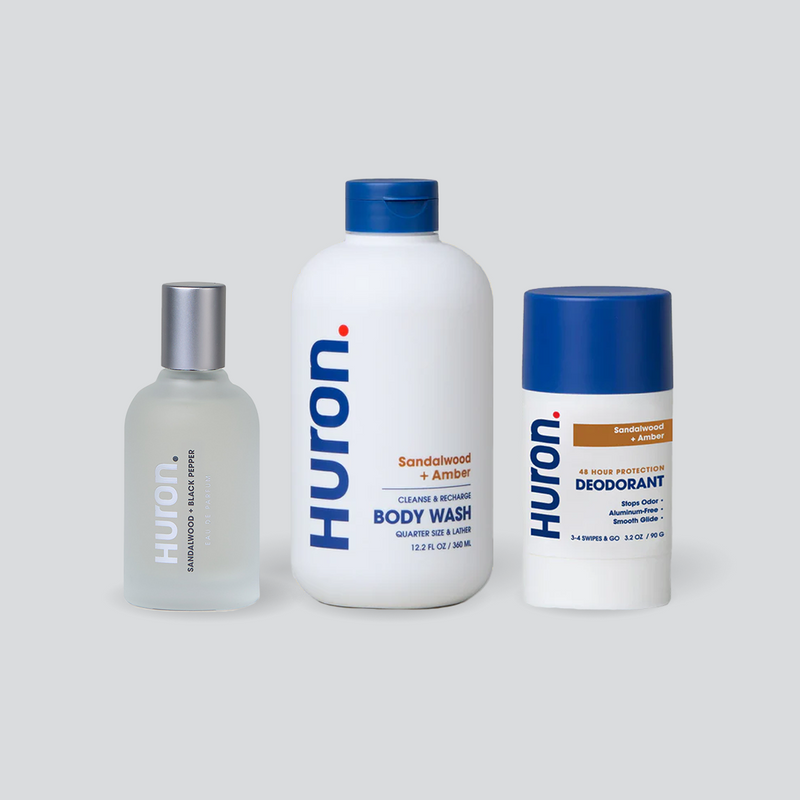 Three Huron products on gray background: Sandalwood + Black Pepper body wash and cologne, and Sandalwood + Amber deodorant. #scent_sandalwood + amber
