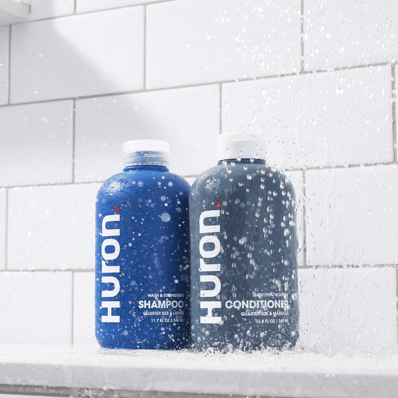 Huron SHAMPOO (WASH & STRENGTHEN) and CONDITIONER (SMOOTH & NOURISH), 11.7 FL OZ / 345 ML and 11.8 FL OZ / 349 ML, in shower.